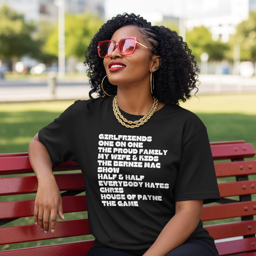 Woman sitting on a bench wearing a black t-shirt with text, outdoors.
