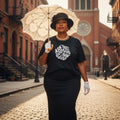 Woman holding an umbrella and wearing a black t-shirt with text, standing on a street with a brick building in the background.