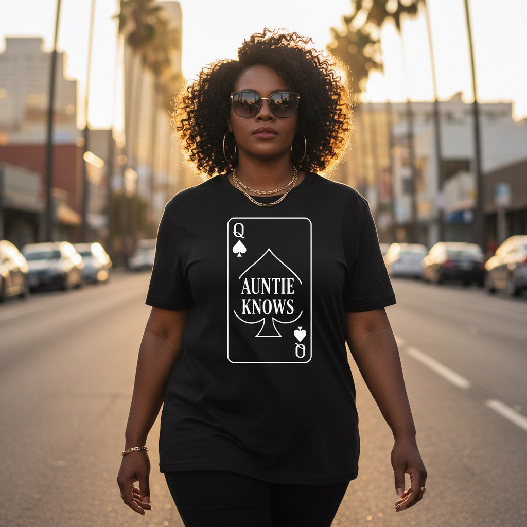 Person wearing a black t-shirt with 'Auntie Knows' design on a city street.
