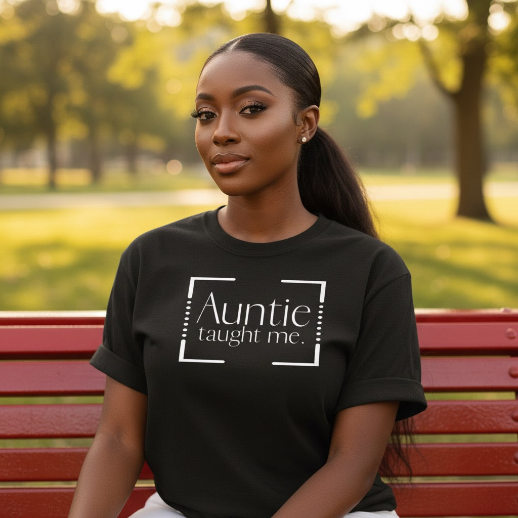 Woman wearing a black t-shirt with 'Auntie taught me' text in a park.