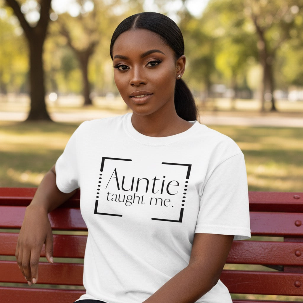 Woman wearing a white t-shirt with 'Auntie taught me' text in a park.