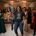 Woman in a black t-shirt with 'Boots on the Ground' text, holding a fan, in a formal event setting.