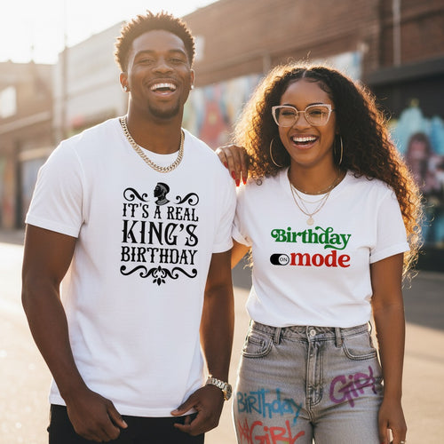 Two people wearing white t-shirts with humorous text designs outdoors.