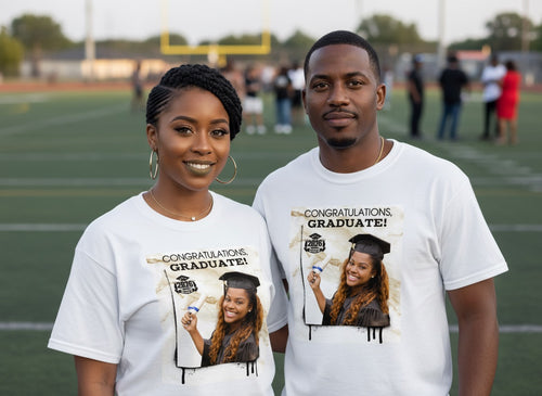 Two people wearing t-shirts with a graduation-themed design on a sports field.