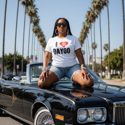 Woman sitting on a classic car with palm trees in the background