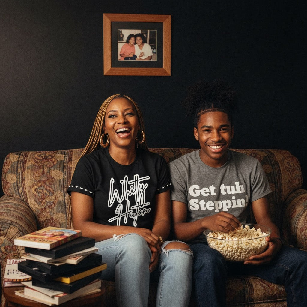 Two people sitting on a couch with books and popcorn, smiling at the camera.