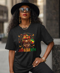 Woman wearing a black t-shirt with a colorful graphic and 'JUNETEENTH' text, sitting outdoors.