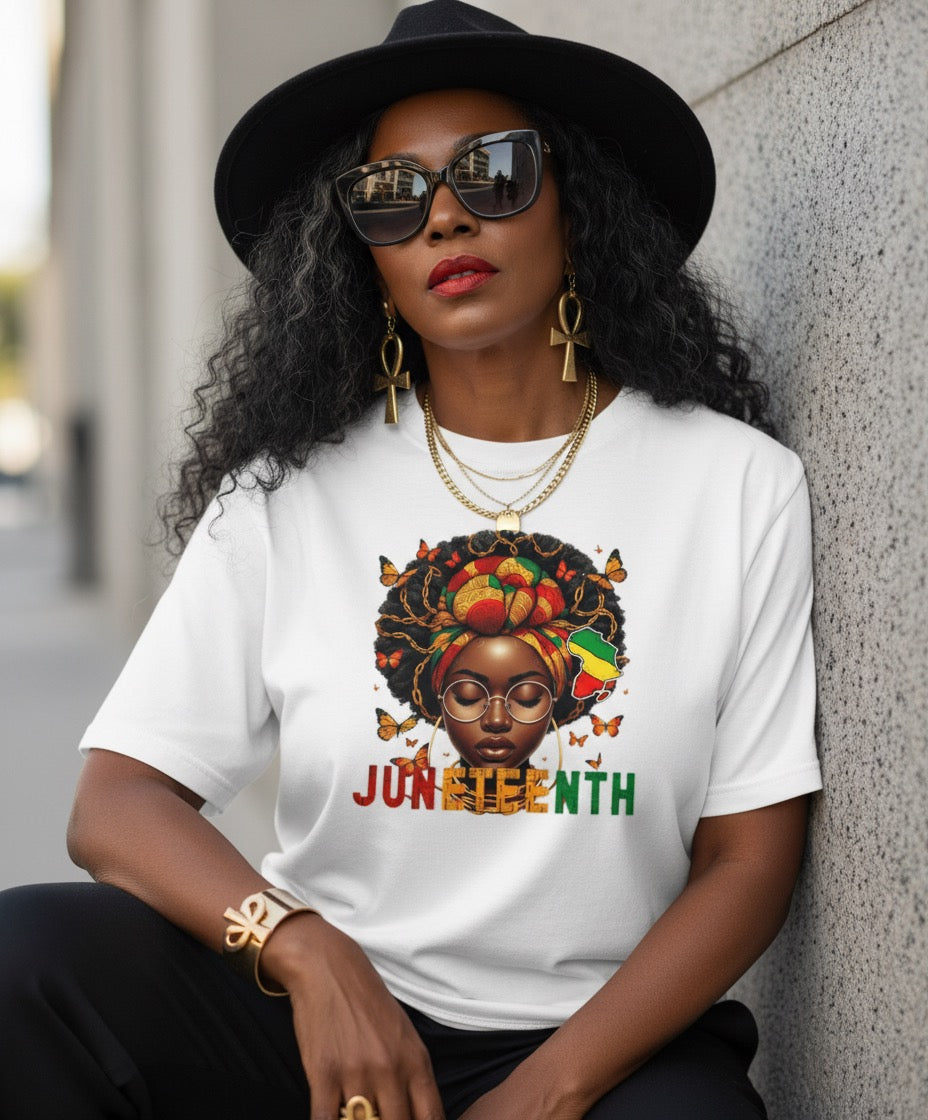 Woman wearing a white t-shirt with a Juneteenth design, sitting against a wall.