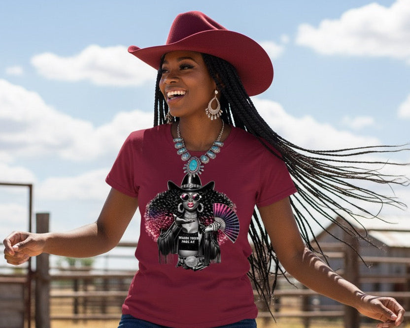 Woman wearing a red t-shirt with a graphic design, blue jeans, and a red cowboy hat in an outdoor setting.