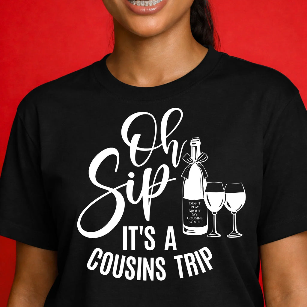 Woman wearing black graphic t-shirt with 'Oh Sip It's a Cousins Trip' wine bottle and glasses design