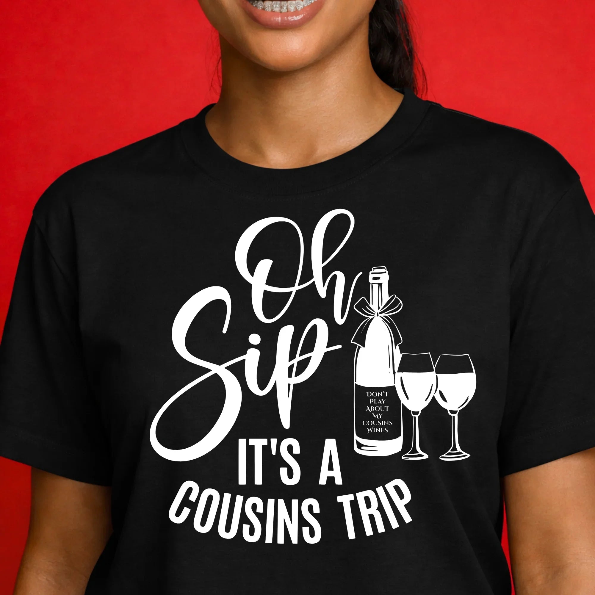 Woman wearing black graphic t-shirt with 'Oh Sip It's a Cousins Trip' wine bottle and glasses design