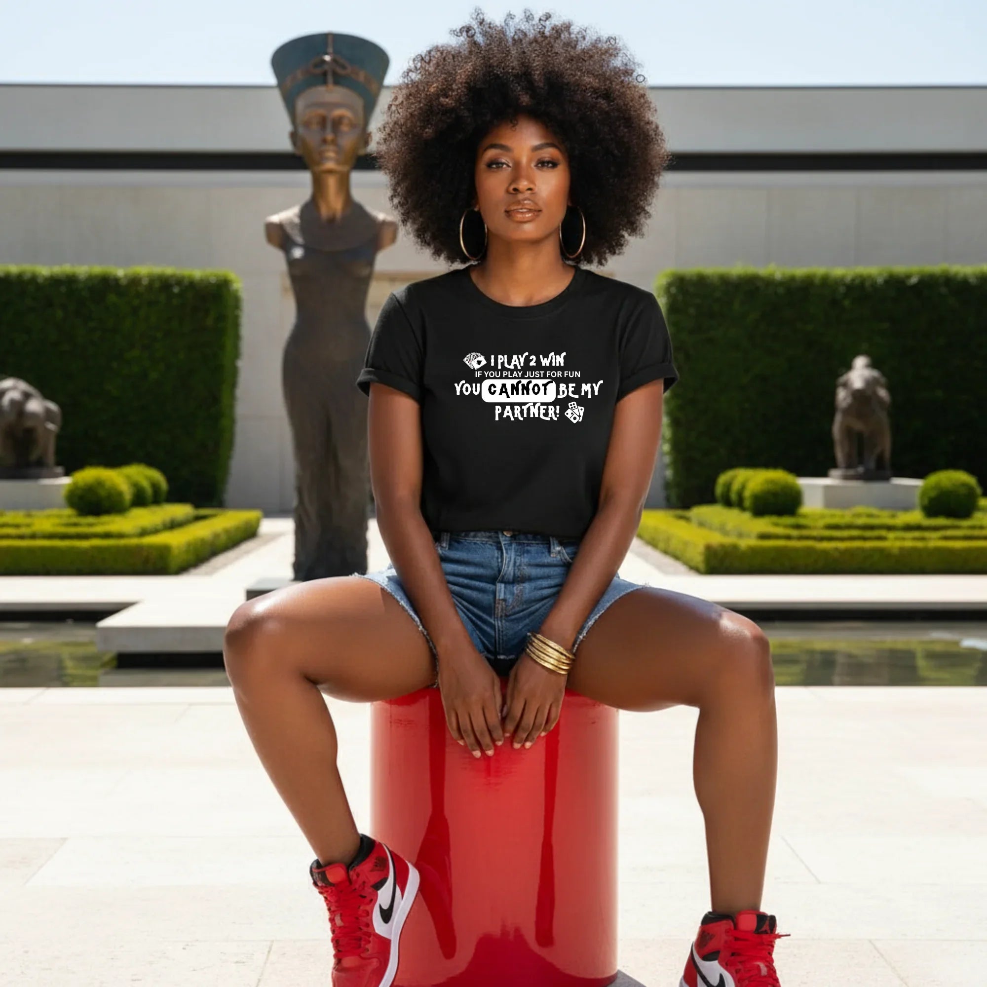 Woman in black graphic tee with 'I play 2 win' text, sitting outdoors, Legacy 4 Xavier shirt