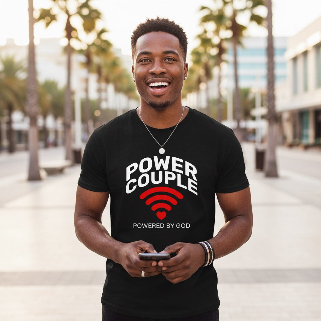 Man wearing a black t-shirt with 'Power Couple' text, standing outdoors with palm trees in the background.