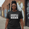 Woman wearing black graphic T-shirt that says 'Somebody's Bougie A$$ Mama' outdoors