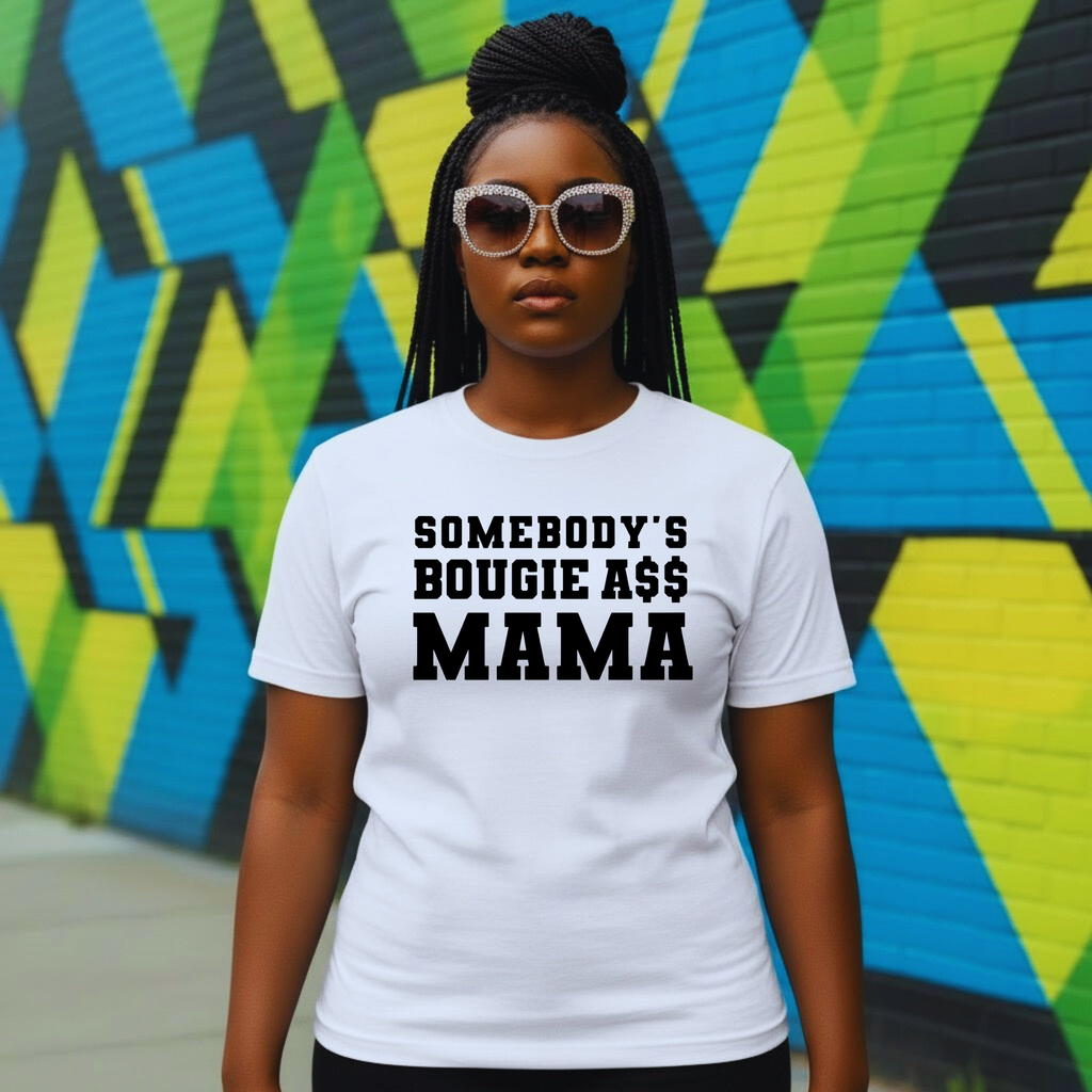 Woman in white graphic t-shirt with 'Somebody's Bougie A$$ Mama' text, urban mural background
