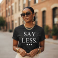 Woman wearing a black t-shirt with 'SAY LESS' text on a street.