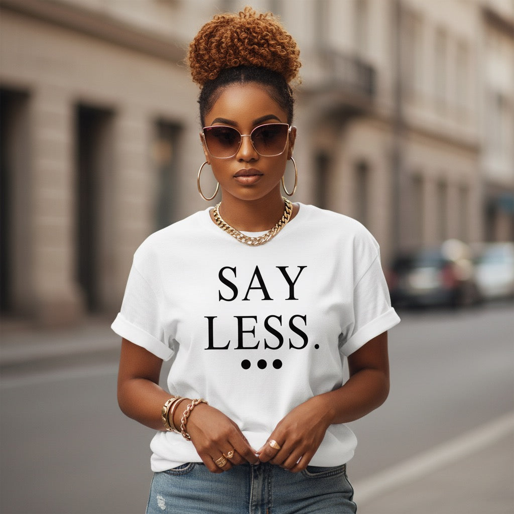 Woman wearing a white t-shirt with 'SAY LESS' text on a city street.