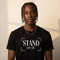Person wearing a black t-shirt with 'STAND ON IT.' text against a neutral background